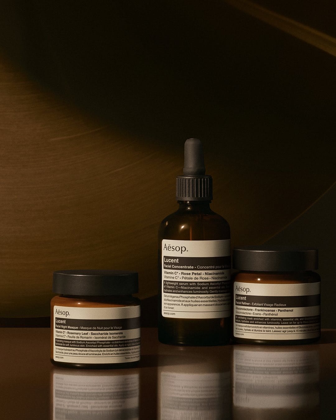 Aesop skincare product photo: amber brown, black and cream, glass, soft light, image 1 of 3
