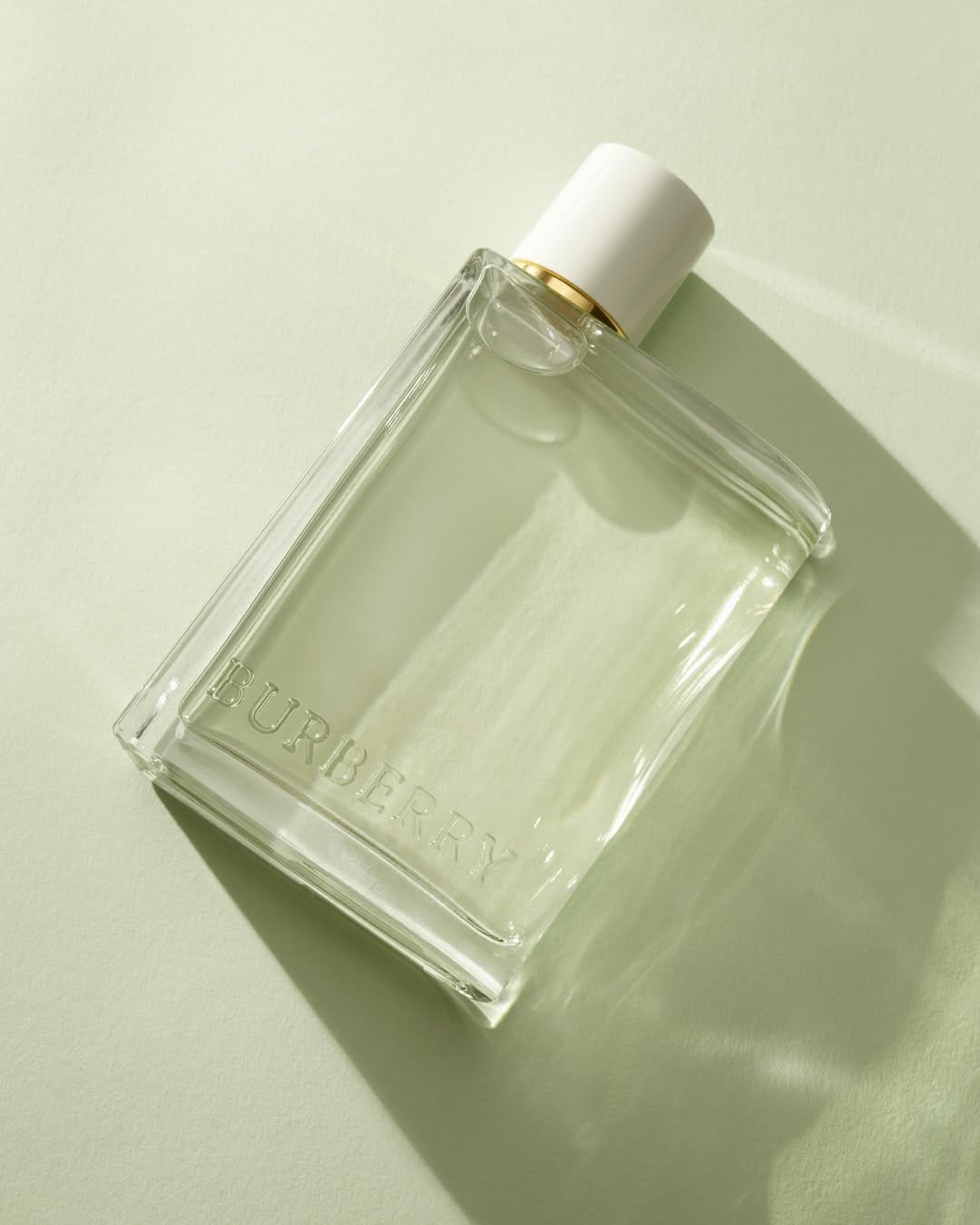 Burberry Her fragrance product photo: clear glass, white cap and pale pear green, glass, soft light, image 3 of 3