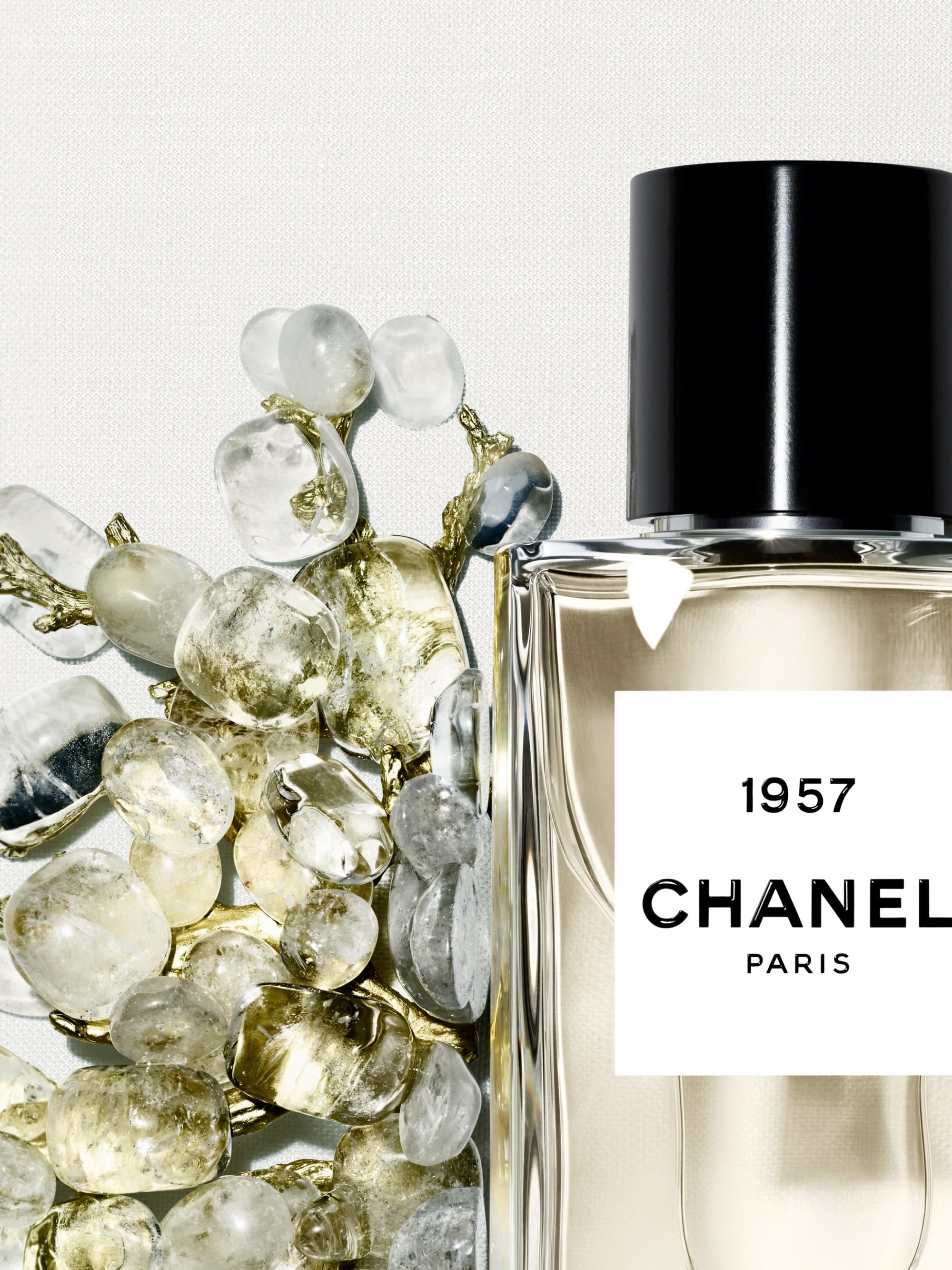Chanel Les Exclusifs product photo: clear glass, pale champagne, black cap and chrome, glass and stone, soft light