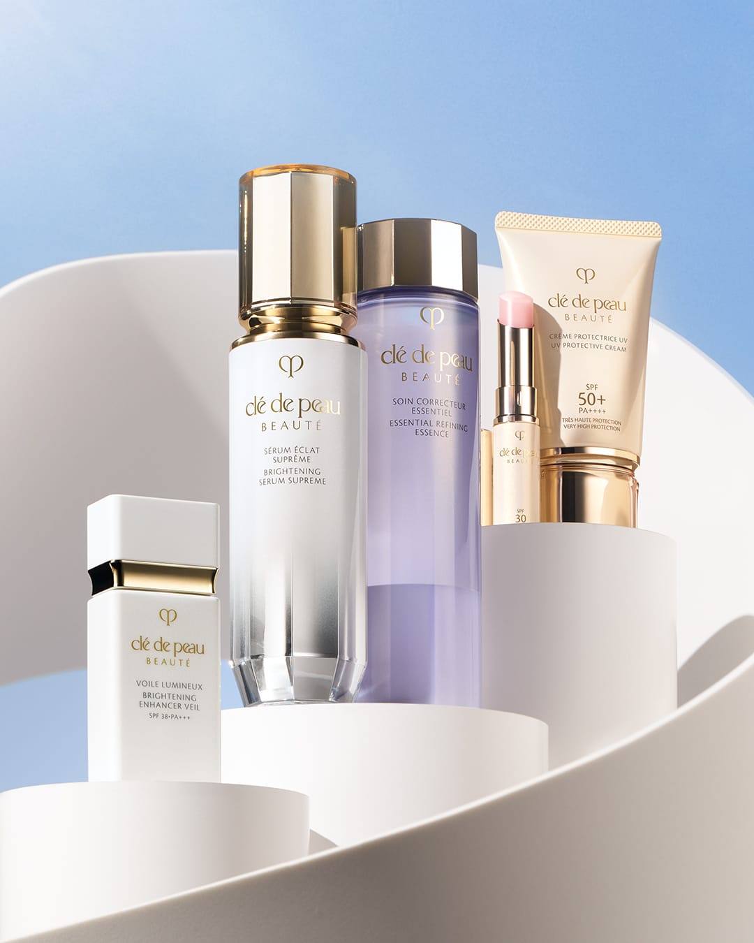 Clé de Peau Beauté skincare product photo: pearl white, gold cap and lavender, plastic, studio light