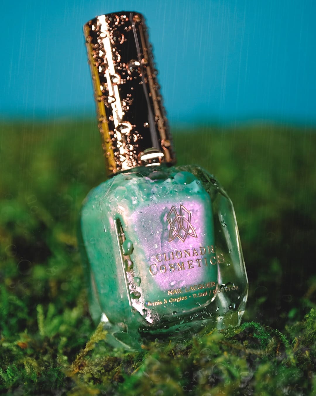 Clionadh Cosmetics' Ophelia product photo: mint green, antique gold and pink shimmer, glass, dramatic light