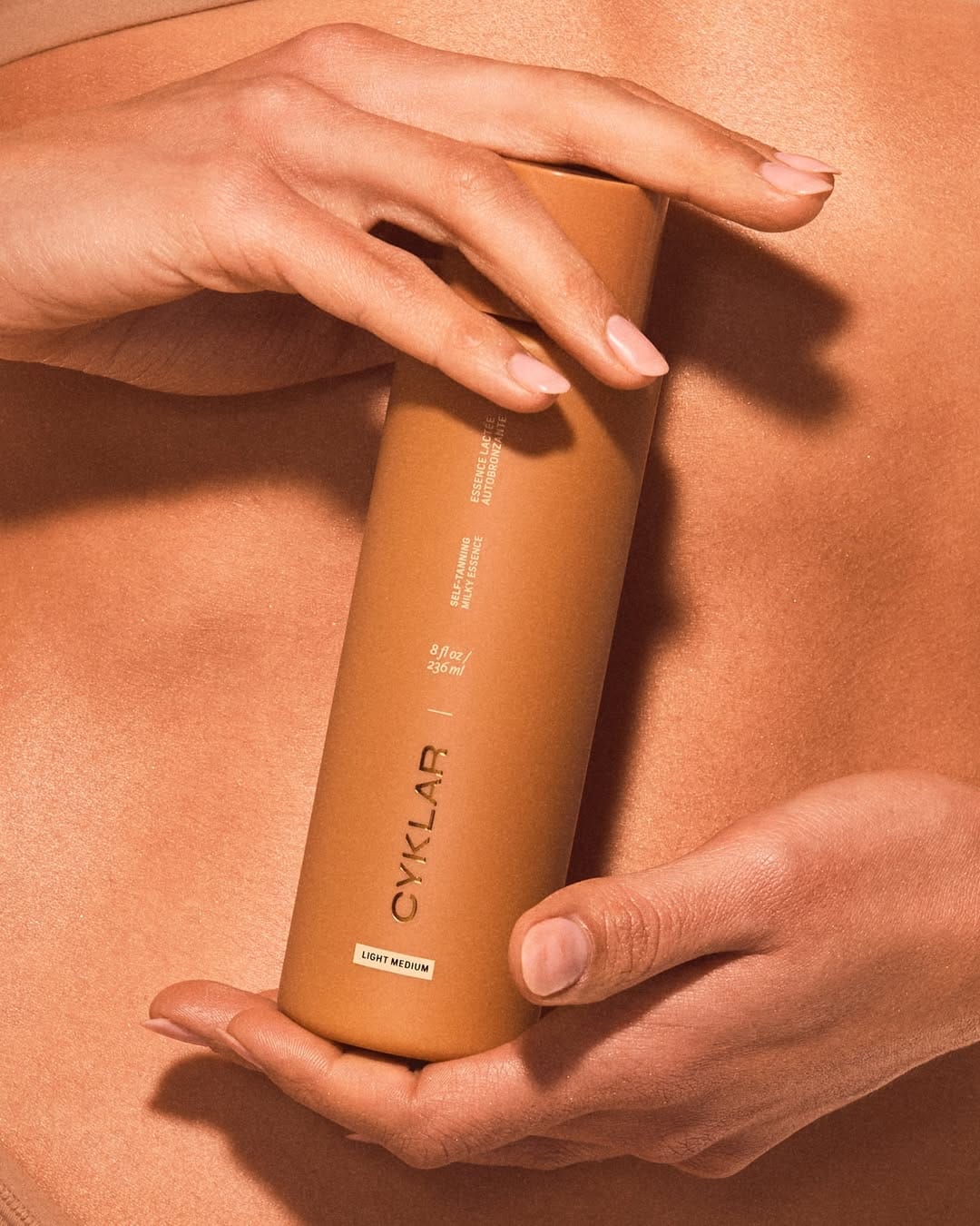 CYKLAR bodycare product photo: bronze brown, caramel tan and cream, plastic and skin, studio light, image 2 of 5
