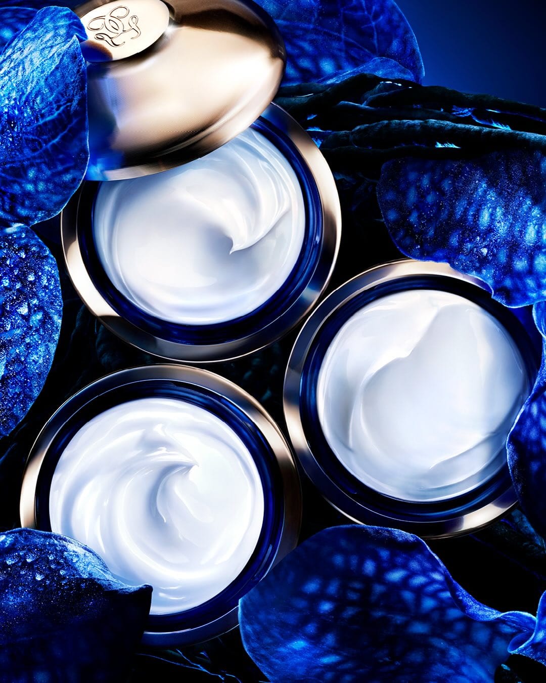 Guerlain skincare product photo: midnight blue, rose gold lid and cream white, glass, studio light