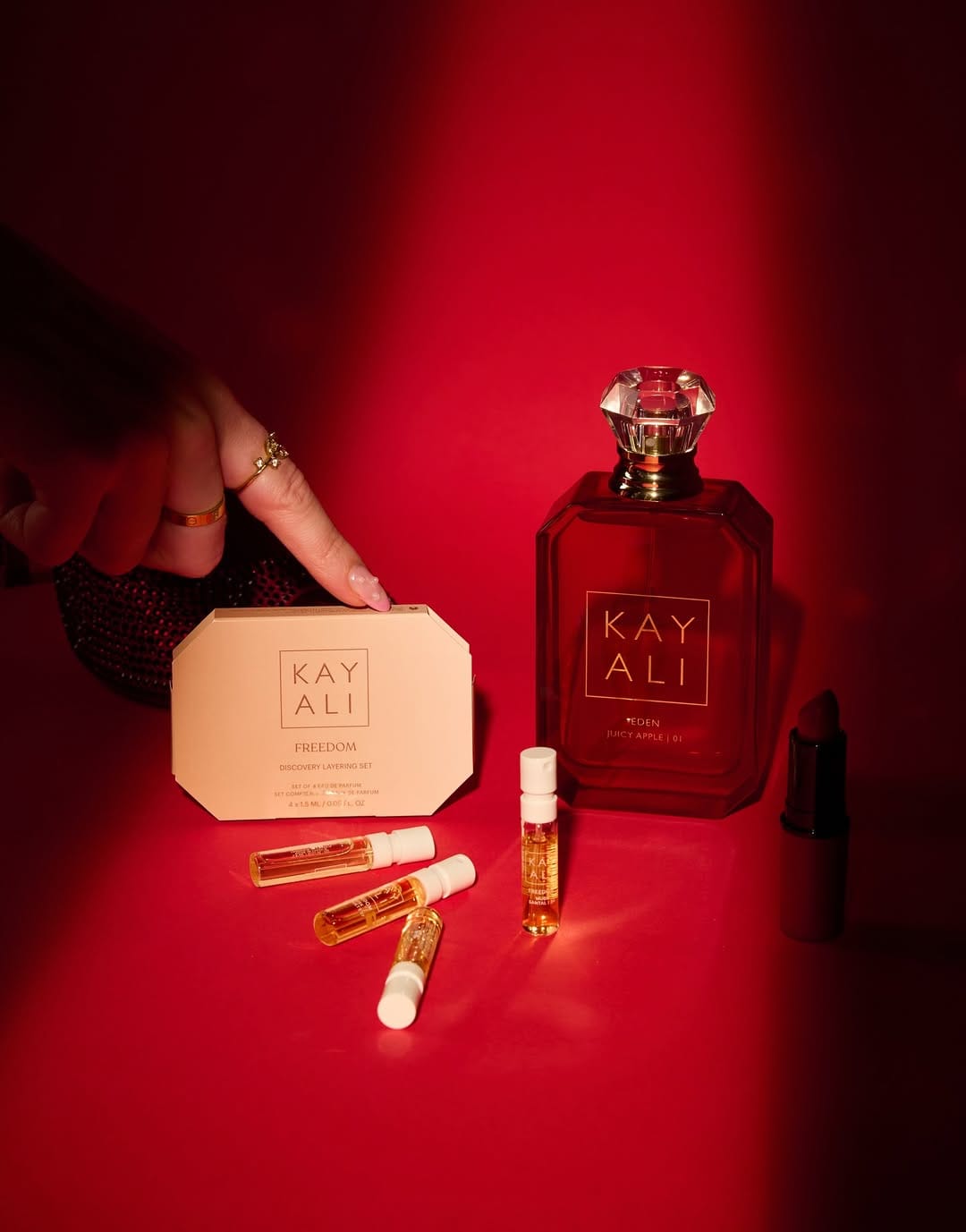 Kayali fragrance product photo: ruby red, peach and rose pink, glass, dramatic light