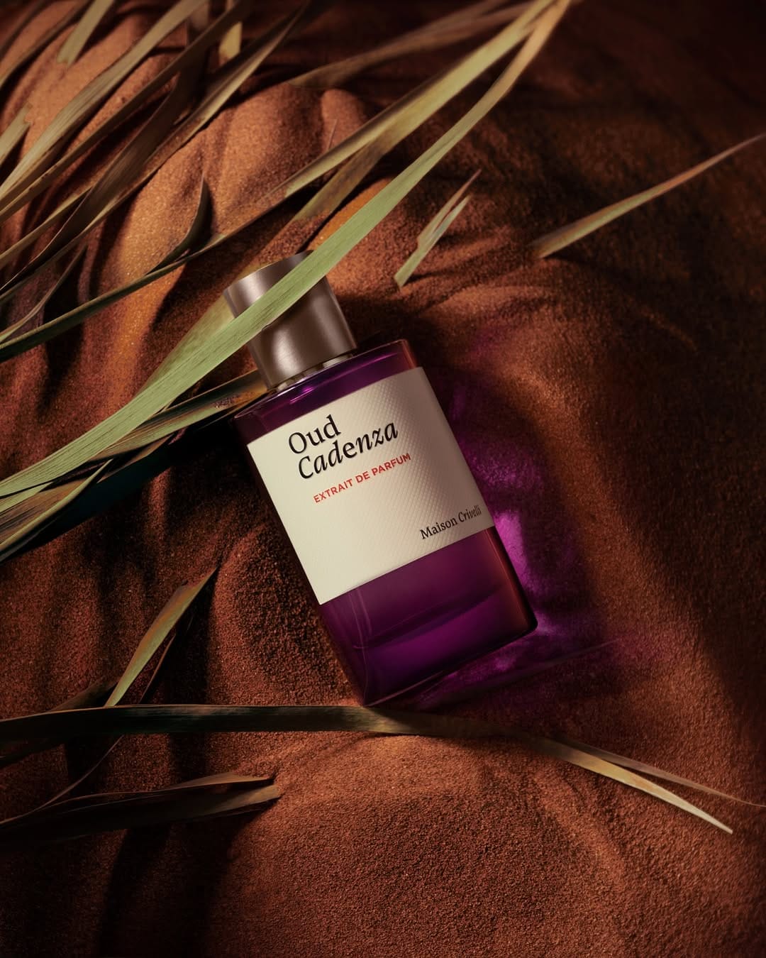 Maison Crivelli Oud Maracujá product photo: cobalt blue, emerald green, violet and cream label, sand, soft light, image 5 of 6