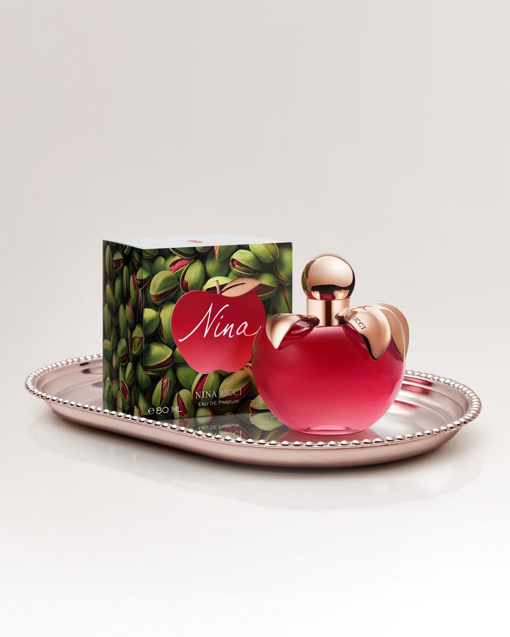 Nina Ricci's anniversary parfum product photo: ruby red, rose gold and blush pink, metal, soft light, image 1 of 5